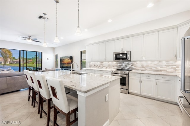 kitchen featuring appliances with stainless steel finishes, a kitchen island with sink, sink, pendant lighting, and white cabinetry