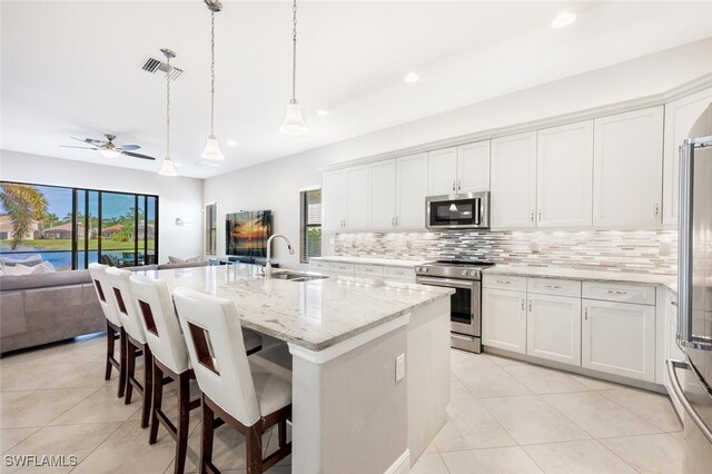 kitchen with sink, white cabinetry, decorative light fixtures, a center island with sink, and appliances with stainless steel finishes