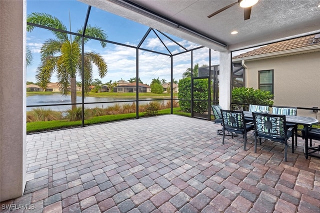 view of patio / terrace featuring a water view, ceiling fan, and a lanai