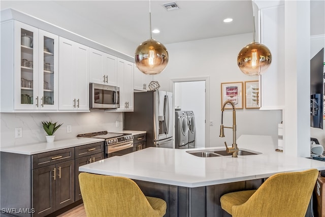 kitchen with stainless steel appliances, a breakfast bar area, separate washer and dryer, and hanging light fixtures