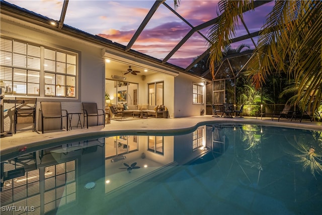 pool at dusk with ceiling fan, a lanai, a patio area, and an outdoor living space