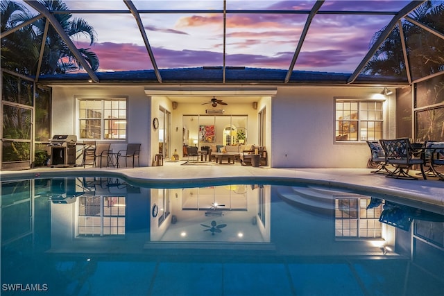 pool at dusk with a lanai, grilling area, a patio, and ceiling fan