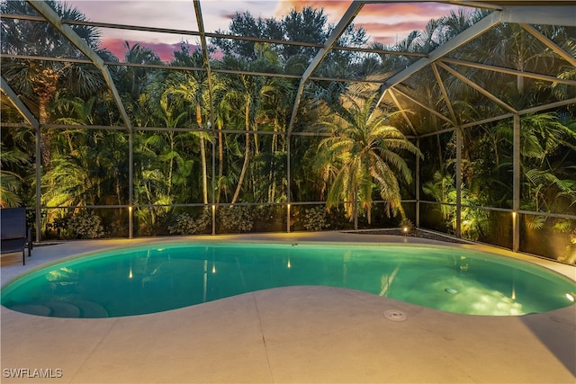 pool at dusk featuring a patio area and a lanai