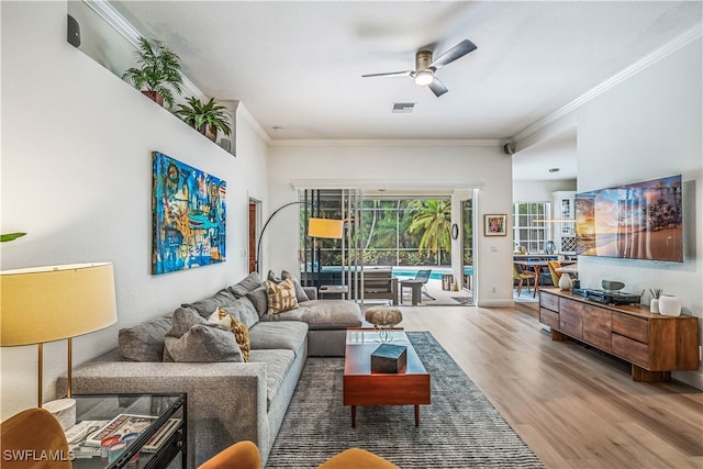 living room with ornamental molding, wood-type flooring, and ceiling fan