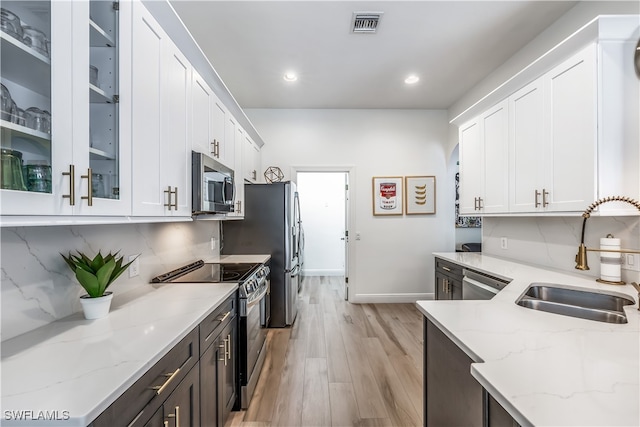 kitchen featuring light hardwood / wood-style flooring, stainless steel appliances, sink, light stone countertops, and white cabinets