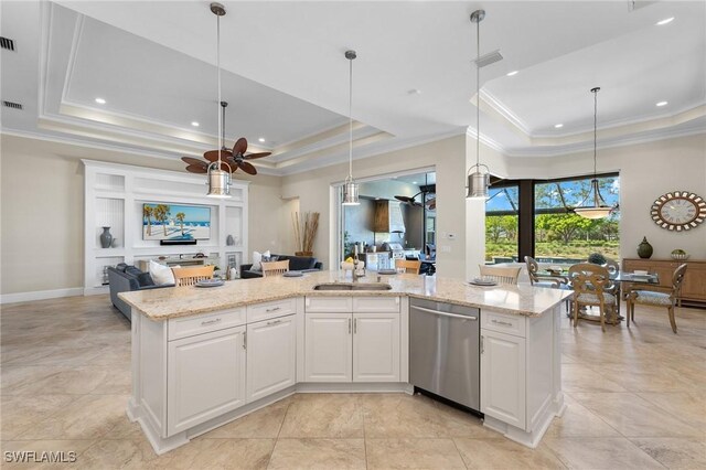 kitchen with a tray ceiling, stainless steel dishwasher, a kitchen island with sink, and white cabinetry