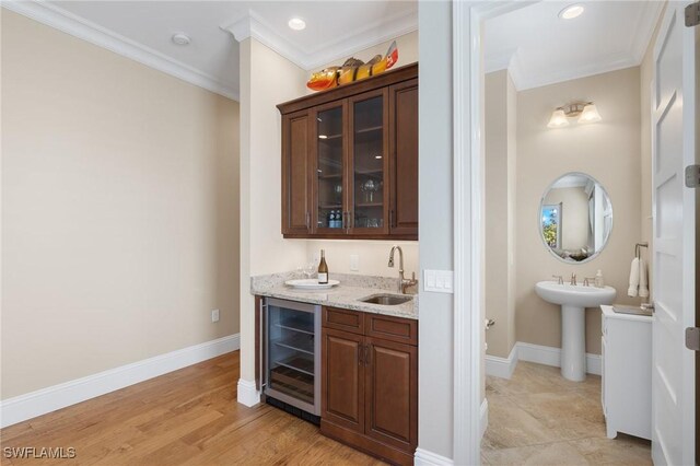 bar featuring dark brown cabinetry, wine cooler, ornamental molding, and sink