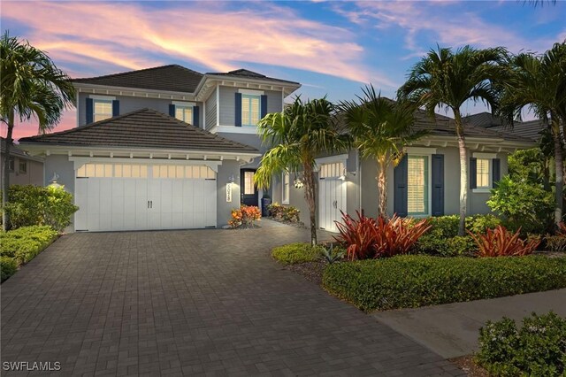 view of front facade featuring an attached garage, decorative driveway, and stucco siding