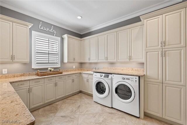 laundry area featuring washing machine and clothes dryer, sink, cabinets, and ornamental molding