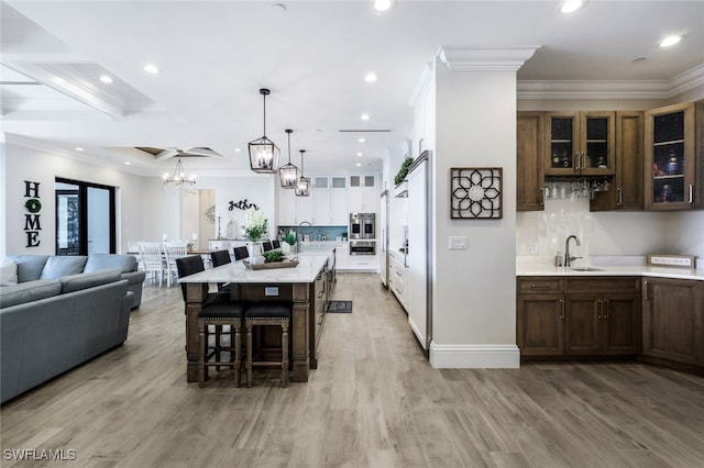 interior space featuring beamed ceiling, light hardwood / wood-style flooring, sink, and crown molding