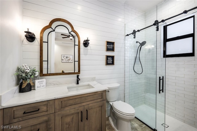 full bathroom featuring a stall shower, vanity, toilet, and ceiling fan