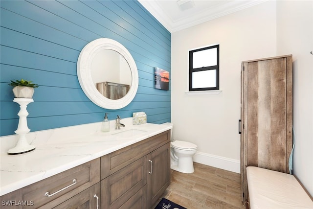 bathroom featuring hardwood / wood-style flooring, toilet, wooden walls, ornamental molding, and vanity