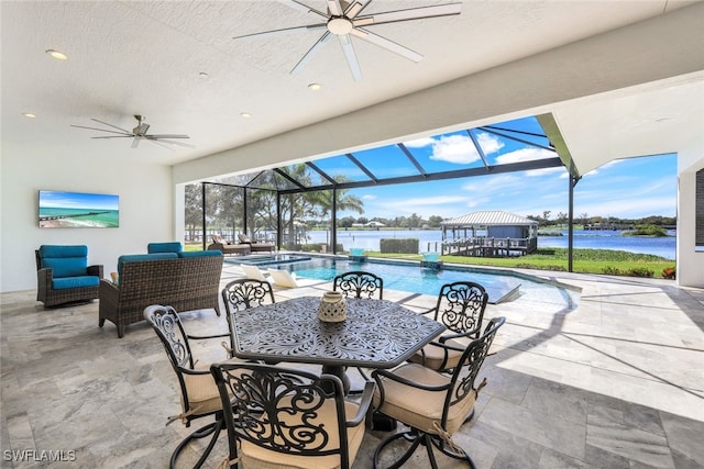 view of patio featuring a water view, ceiling fan, and a lanai