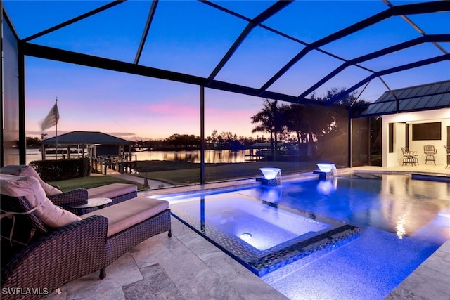 pool at dusk featuring a patio, a lanai, an in ground hot tub, and a water view