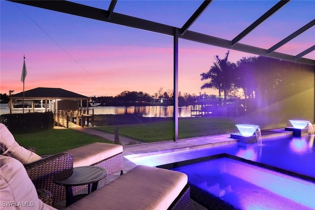 pool at dusk featuring a patio area, a yard, and a water view