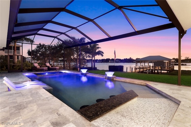 pool at dusk with a jacuzzi, an outdoor pool, a patio, and a water view