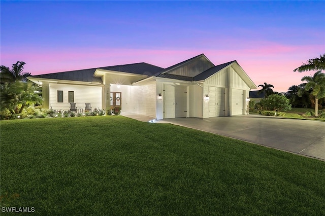 view of front of property with a garage, a front yard, concrete driveway, a standing seam roof, and metal roof
