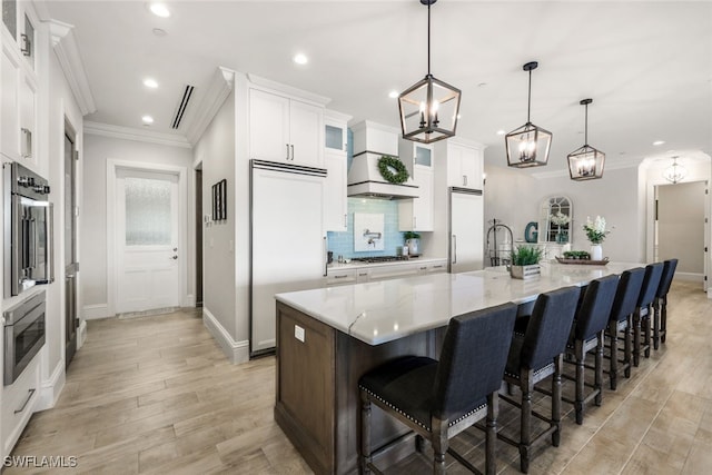 kitchen featuring built in appliances, recessed lighting, white cabinets, light wood-style floors, and ornamental molding