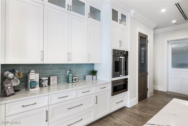 kitchen with light stone countertops, decorative backsplash, white cabinets, dark wood-type flooring, and ornamental molding