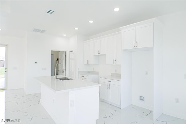 kitchen with white cabinetry, sink, and an island with sink