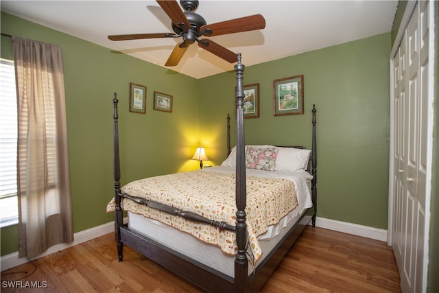 bedroom with multiple windows, wood-type flooring, a closet, and ceiling fan