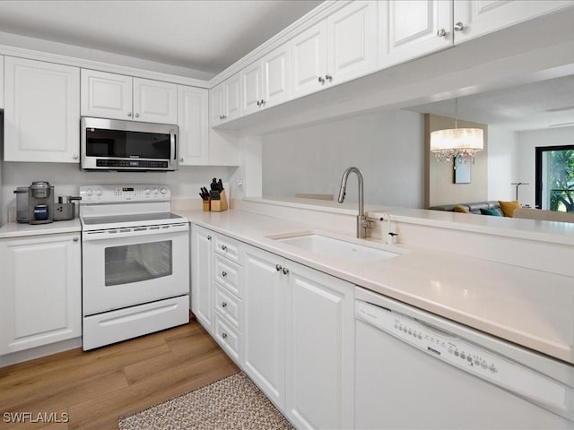 kitchen with sink, white cabinets, a chandelier, and white appliances