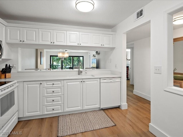 kitchen with sink, white cabinets, white appliances, and light wood-type flooring