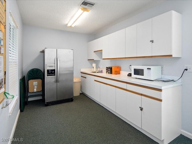 kitchen featuring white cabinetry, stainless steel fridge with ice dispenser, dark carpet, and a textured ceiling