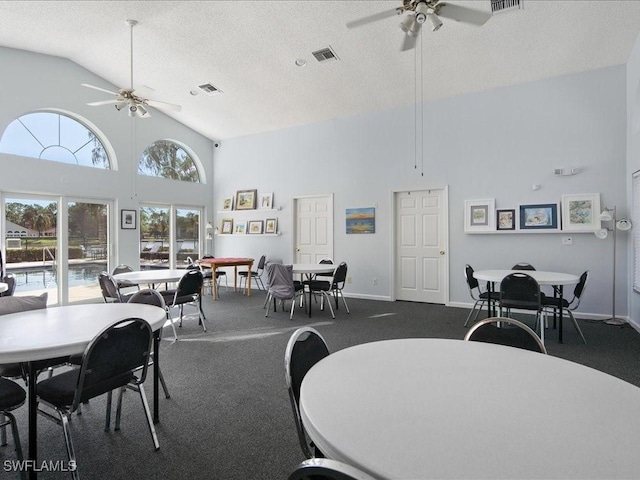 carpeted dining space featuring ceiling fan, a textured ceiling, and high vaulted ceiling