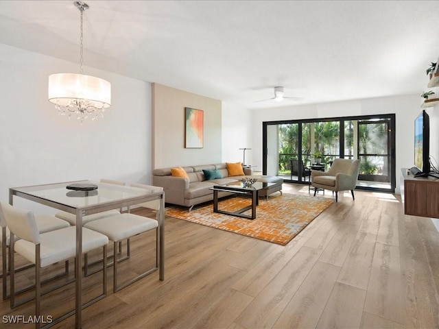 living room with light hardwood / wood-style flooring and ceiling fan with notable chandelier