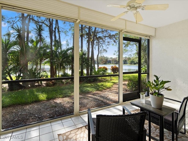 sunroom with ceiling fan and a water view