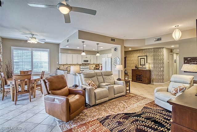 living room featuring ceiling fan, a textured ceiling, and light tile patterned flooring