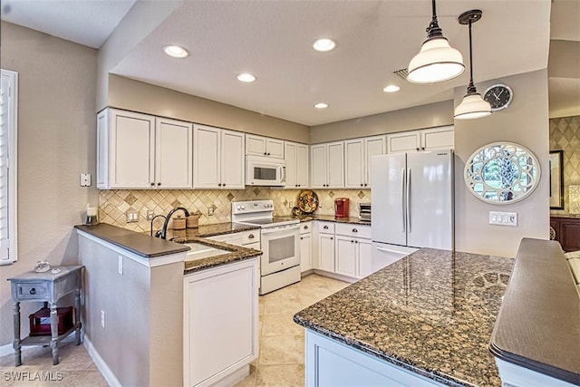 kitchen with white appliances, sink, kitchen peninsula, pendant lighting, and white cabinets