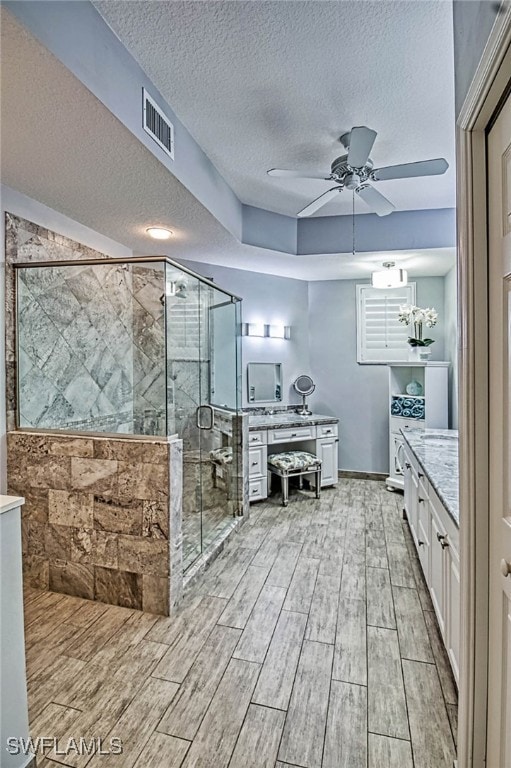 bathroom with a shower with door, ceiling fan with notable chandelier, a textured ceiling, hardwood / wood-style floors, and vanity