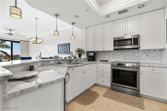 kitchen with sink, kitchen peninsula, appliances with stainless steel finishes, white cabinets, and ornamental molding