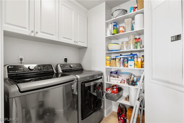 laundry room featuring washer and clothes dryer, light tile patterned flooring, and cabinets