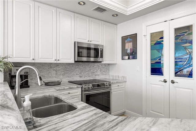 kitchen with white cabinetry, sink, light stone counters, and appliances with stainless steel finishes