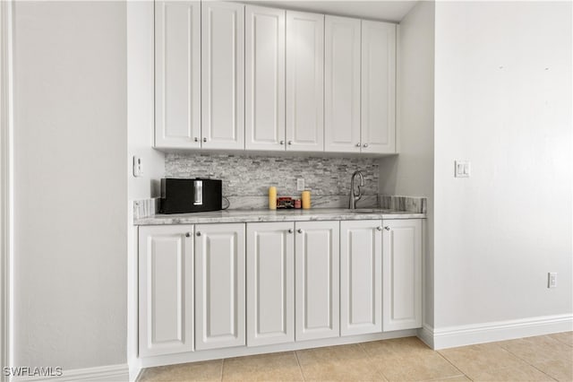 bar with decorative backsplash, sink, white cabinets, and light tile patterned flooring