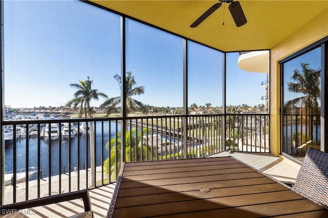 sunroom featuring a water view and ceiling fan