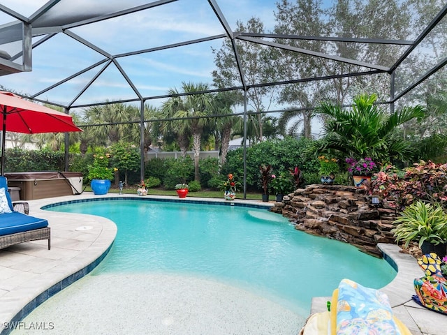 view of swimming pool with a hot tub, glass enclosure, and a patio