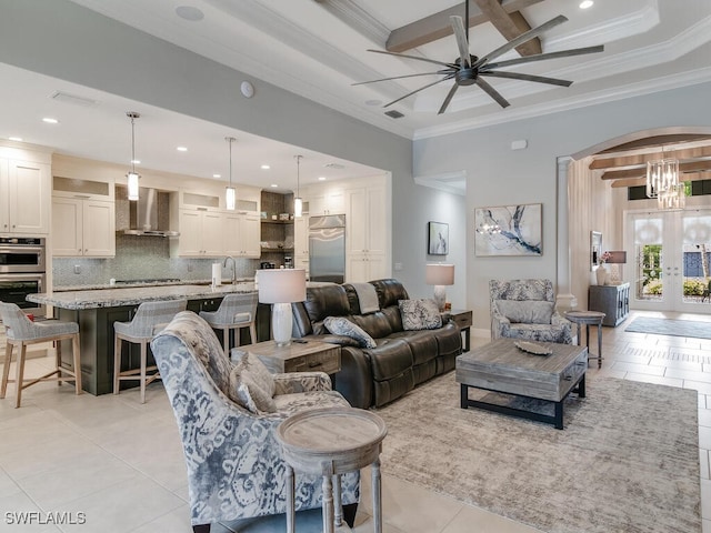 tiled living room with sink, beamed ceiling, ceiling fan with notable chandelier, and crown molding