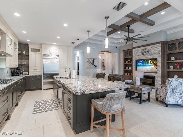 kitchen with stainless steel appliances, white cabinetry, a large island, a breakfast bar area, and beamed ceiling