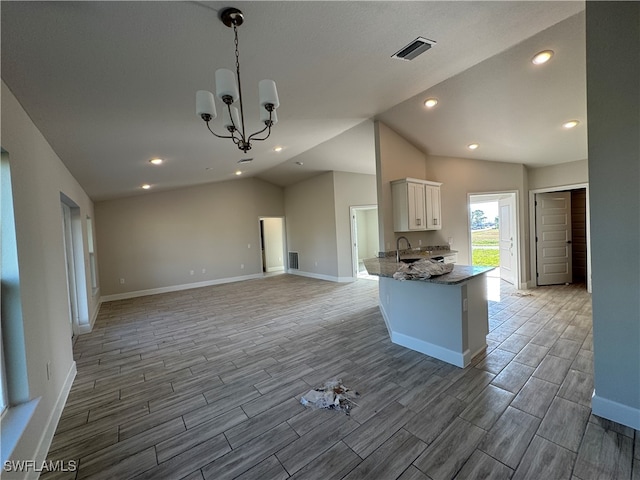 kitchen with stone counters, vaulted ceiling, white cabinetry, wood-type flooring, and a chandelier