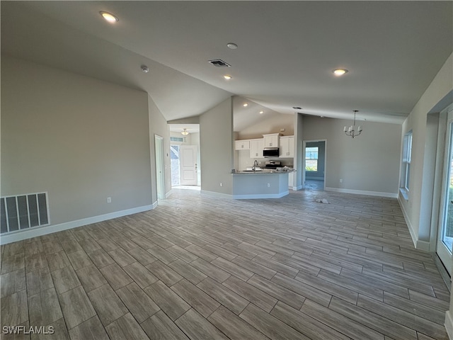 unfurnished living room with vaulted ceiling, an inviting chandelier, light hardwood / wood-style flooring, and sink