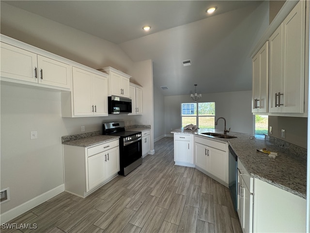 kitchen with kitchen peninsula, stainless steel appliances, vaulted ceiling, sink, and white cabinetry