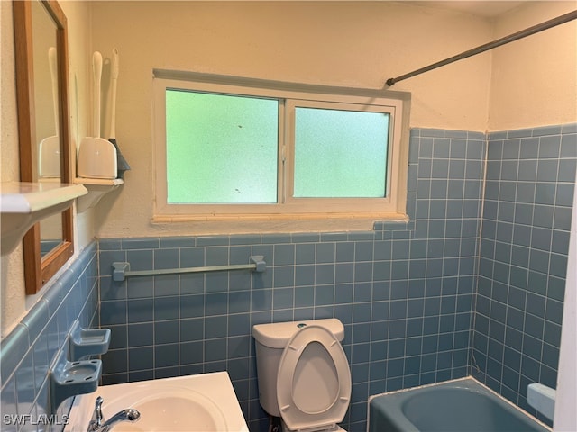 full bathroom with sink, tiled shower / bath combo, toilet, and tile walls