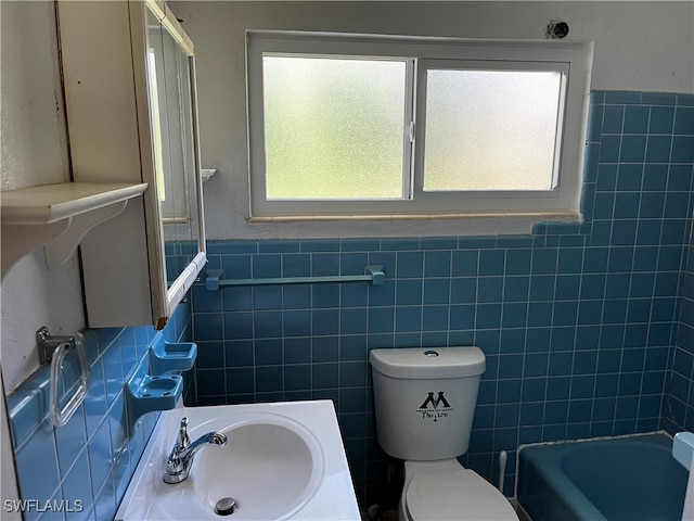 bathroom with sink, a healthy amount of sunlight, and tile walls