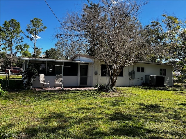 back of property with a lawn and a sunroom