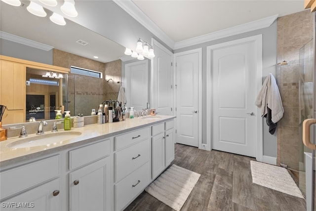 bathroom with wood-type flooring, vanity, a shower with door, and crown molding