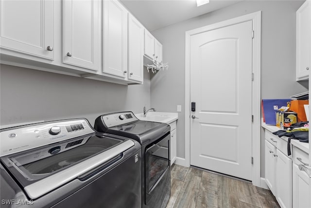 clothes washing area featuring cabinets, washer and dryer, sink, and dark hardwood / wood-style flooring